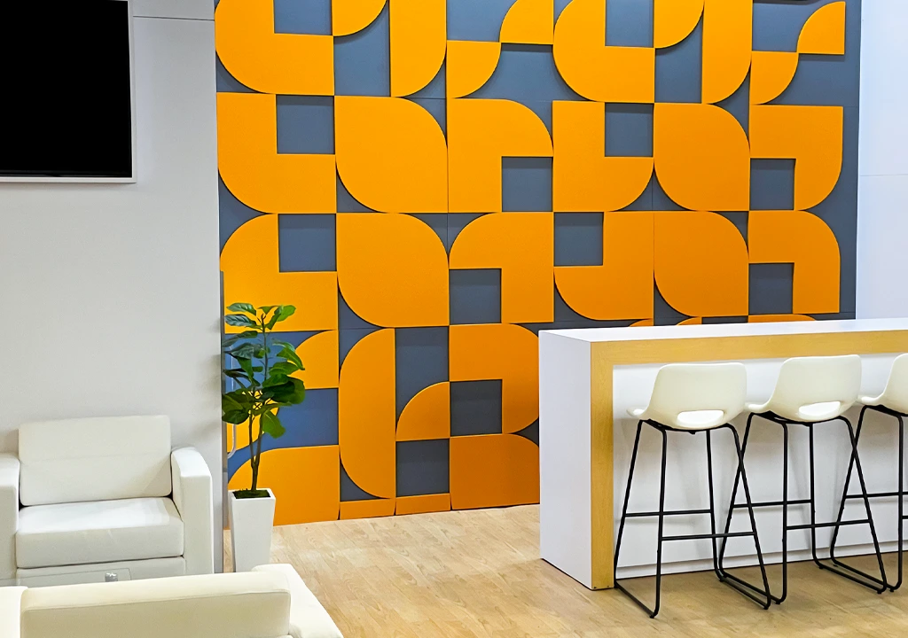 Modern exhibition lounge with orange geometric wall and white seating