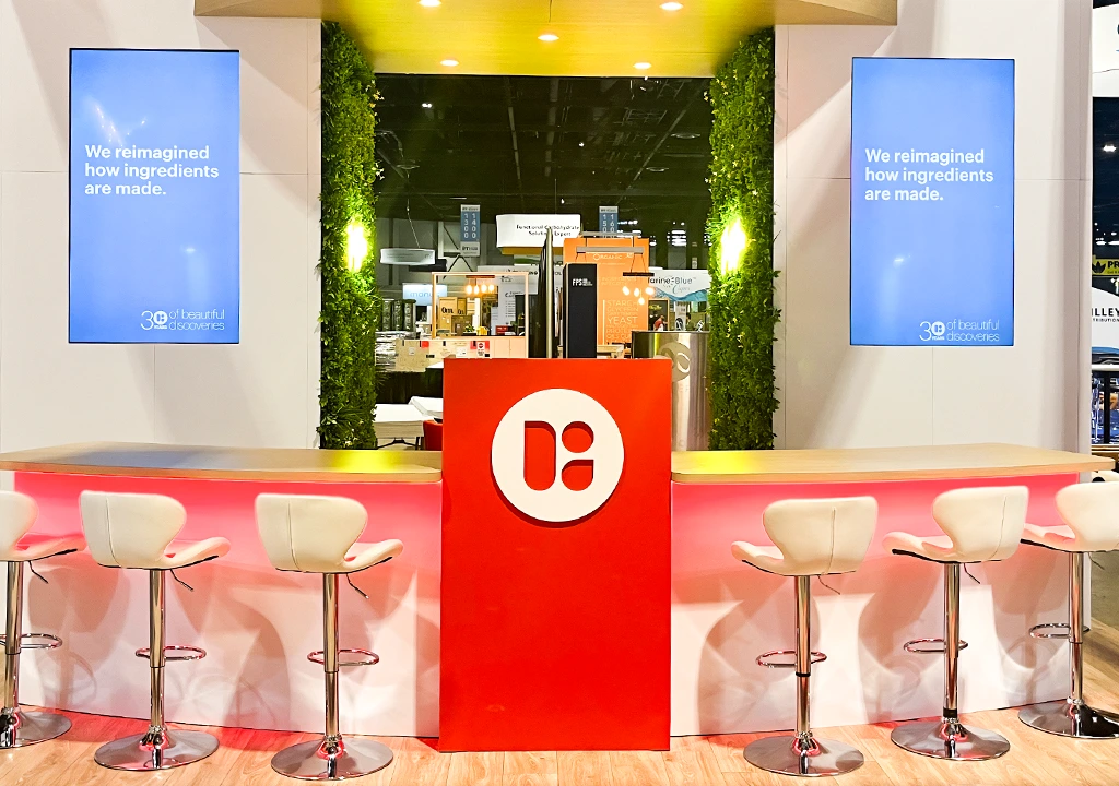 Bright custom exhibition booth with orange counter and green wall