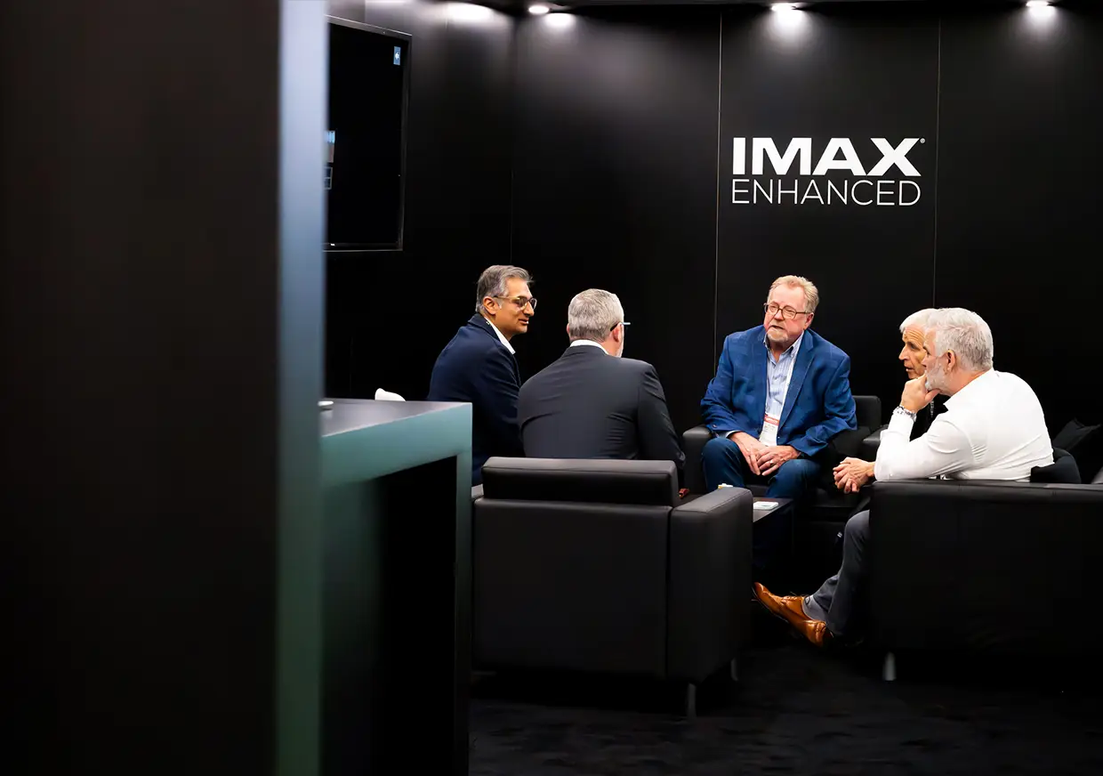 Guests seated in conversation inside the black IMAX Enhanced booth