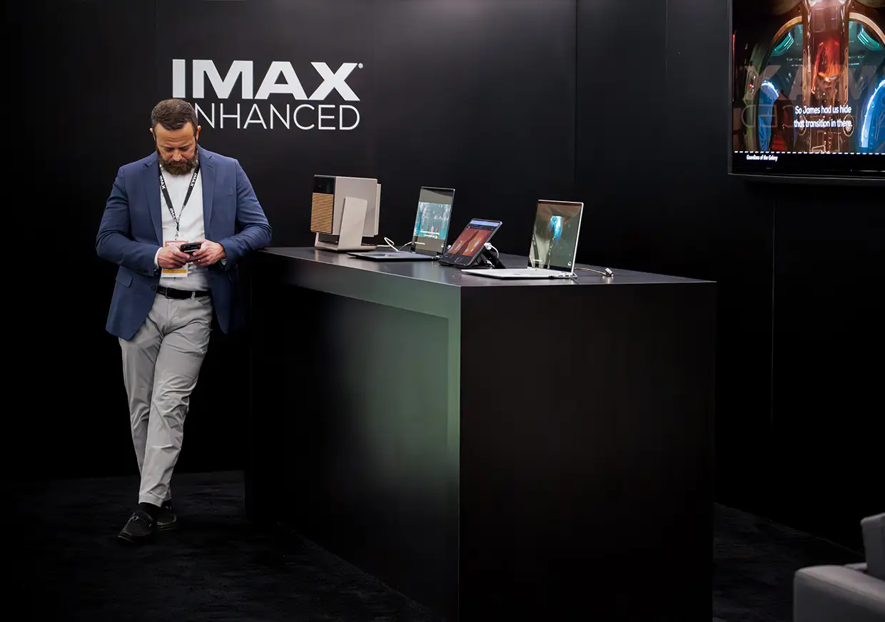 Man standing beside product displays inside the IMAX Enhanced booth