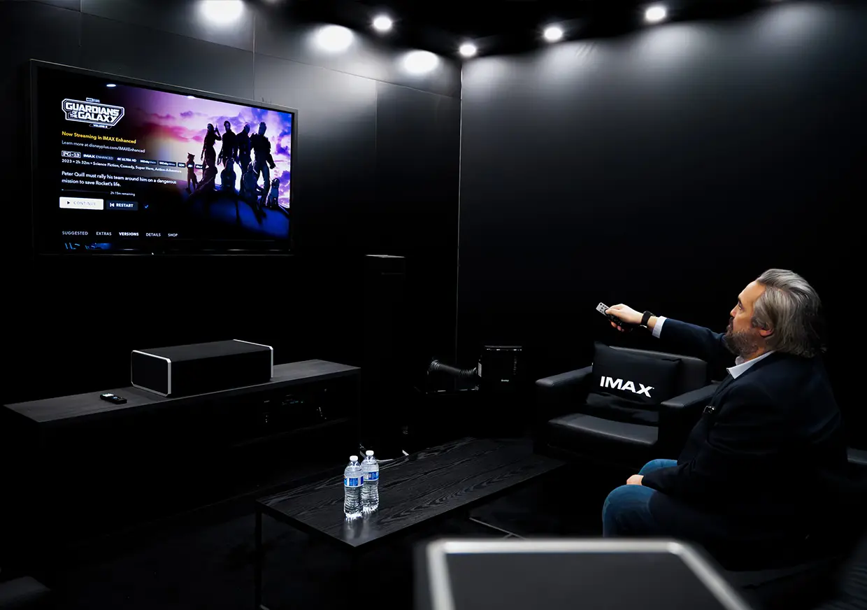 Visitor seated in dark IMAX demonstration room watching screen presentation