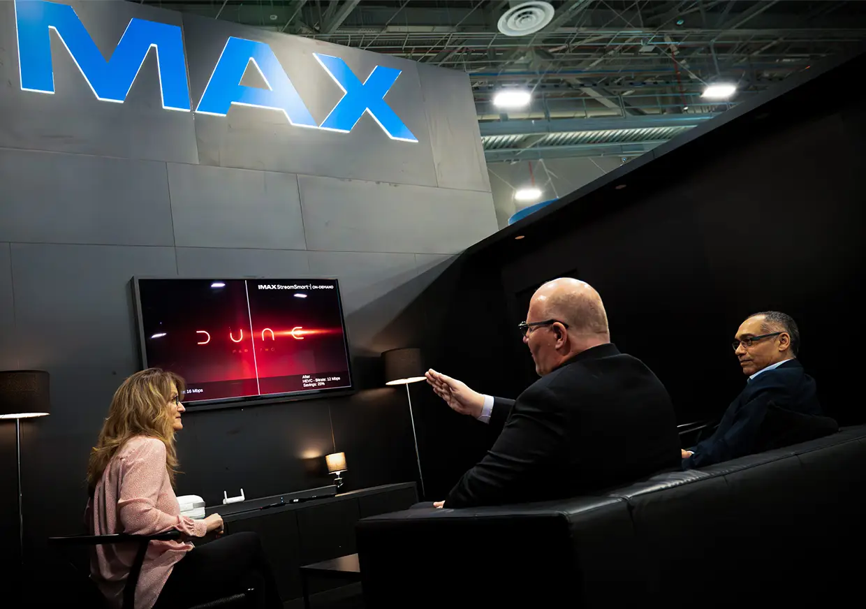 Visitors testing audiovisual equipment inside an IMAX trade show booth