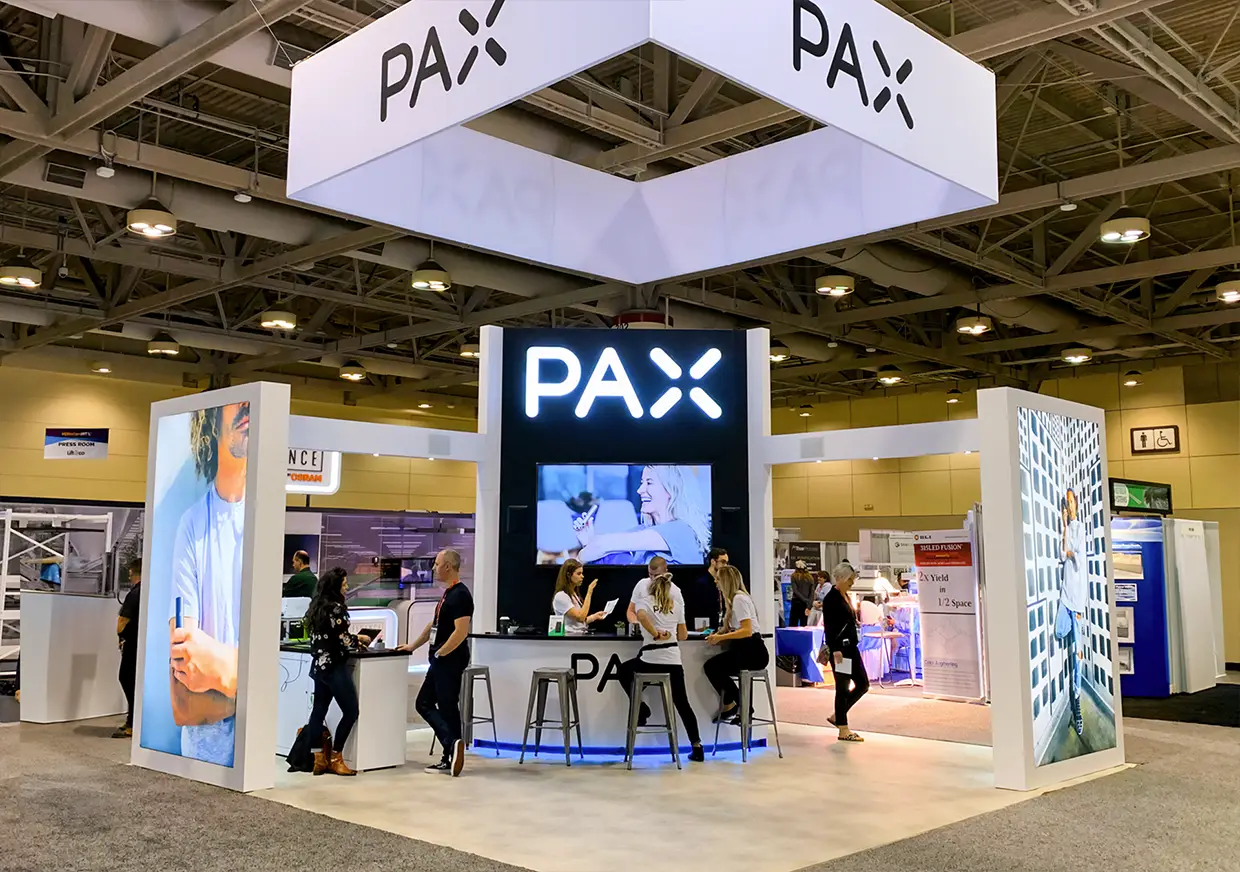 Wide front view of PAX booth with screens and meeting areas
